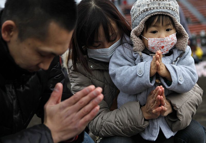 A family prays after arranging candles at a candlelight event in Iwaki, Fukushima