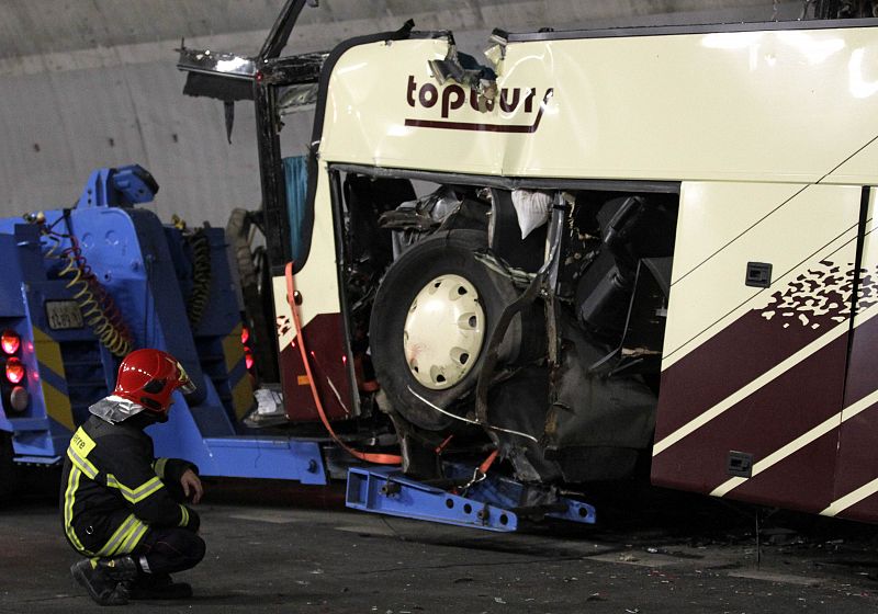 Un bombero junto a los restos del vehículo accidentado. El autobús transportaba a estudiantes belgas