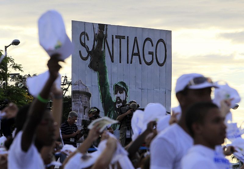 Peregrinos junto a un cartel con la imagen del expresidente cubano Fidel Castro