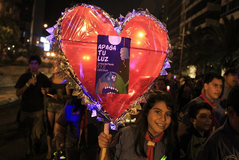 Children march while holding candles during Earth Hour in Lima