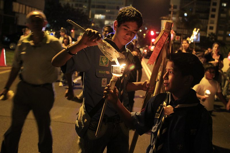 Children light a candle while marching during Earth Hour in Lima