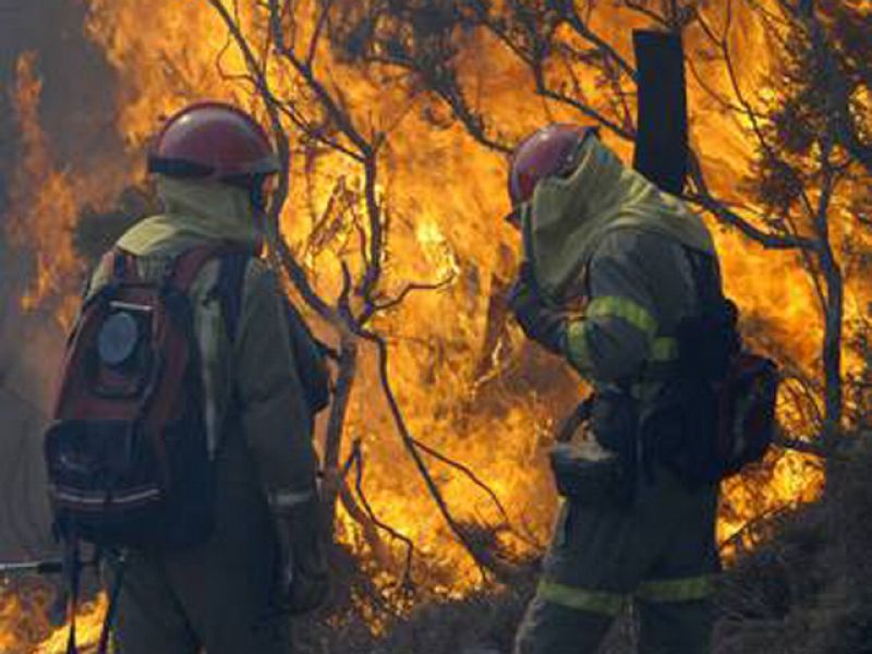 Dos bomberos se protegen del fuego.