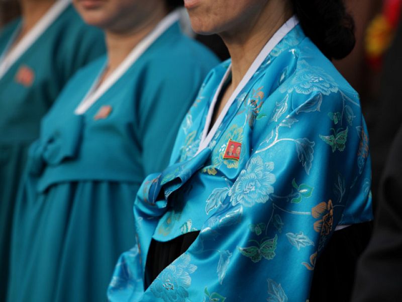 Una mujer norcoreana, con una insignia con los rostros de los líderes del país.