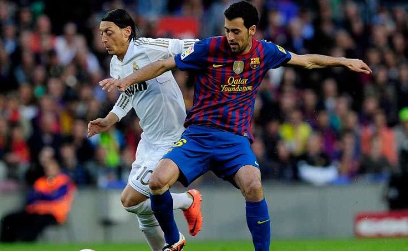 Busquets forcejea con Özil por el balón.