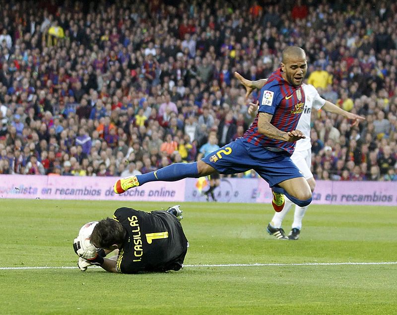 Iker Casillas detiene el balón ante un intento de penetrar del brasileño Dani Alves