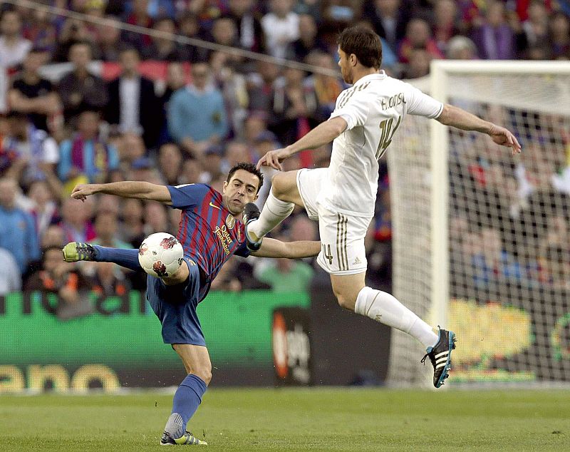 El centrocampista del FC Barcelona Xavi Hernández (i), pelea un balón con el centrocampista del Real Madrid Xabi Alonso