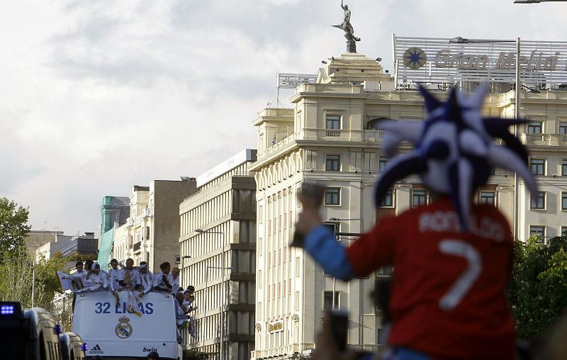 Un niño, con la camiseta roja de Ronaldo, espera a sus ídolos camino de la madrileña plaza de la Cibeles