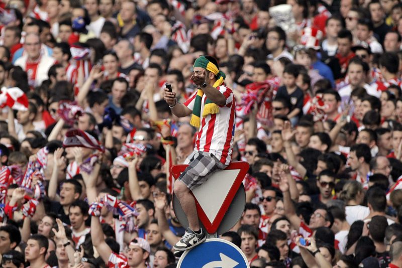 Un aficionado del Atlético de Madrid celebra la Final en una señal de tráfico de la plaza de Neptuno