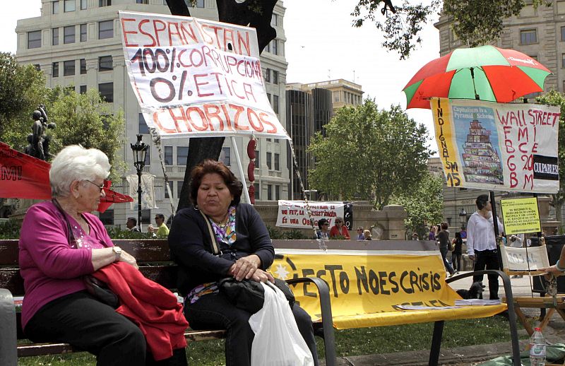 Dos señoras ante los carteles del movimiento del 15M en la plaza de Cataluña.