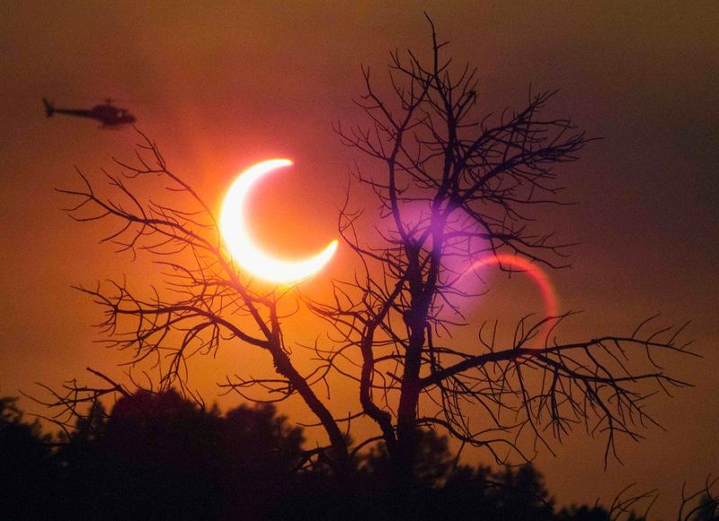 Un helicóptero sobrevuela en frente del eclipse solar en Payson, Arizona