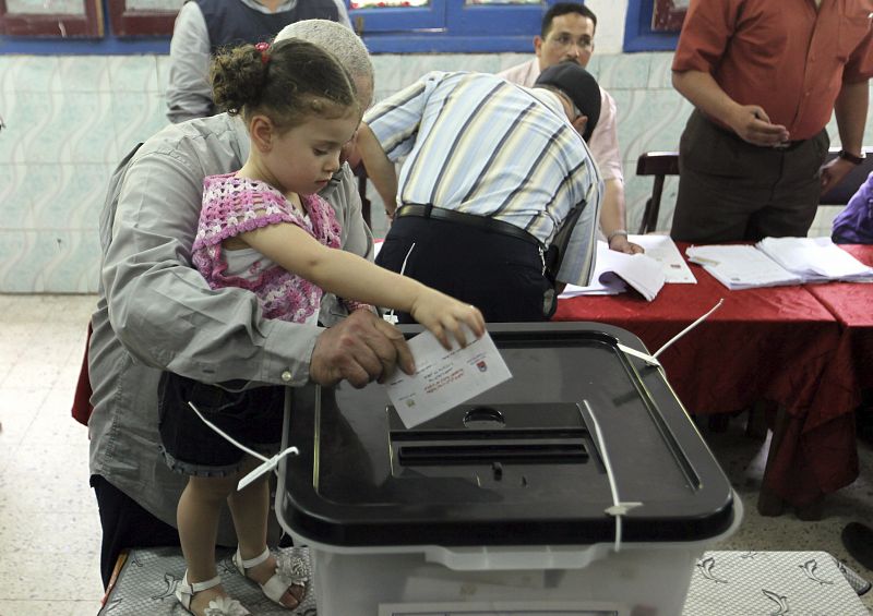 Un hombre egipcio deja que su nieta deposite su voto.