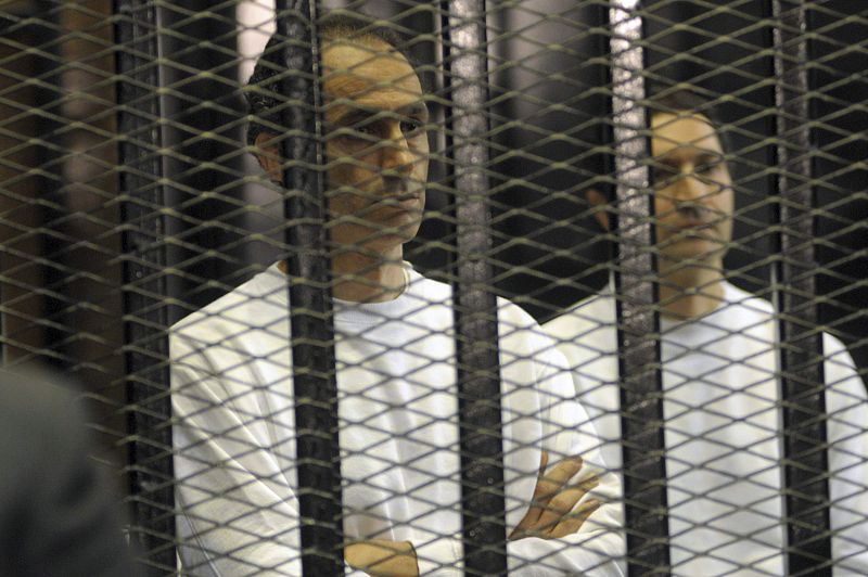 Gamal and Alaa, sons of former Egyptian President Mubarak, stand inside a cage at a courtroom in Cairo