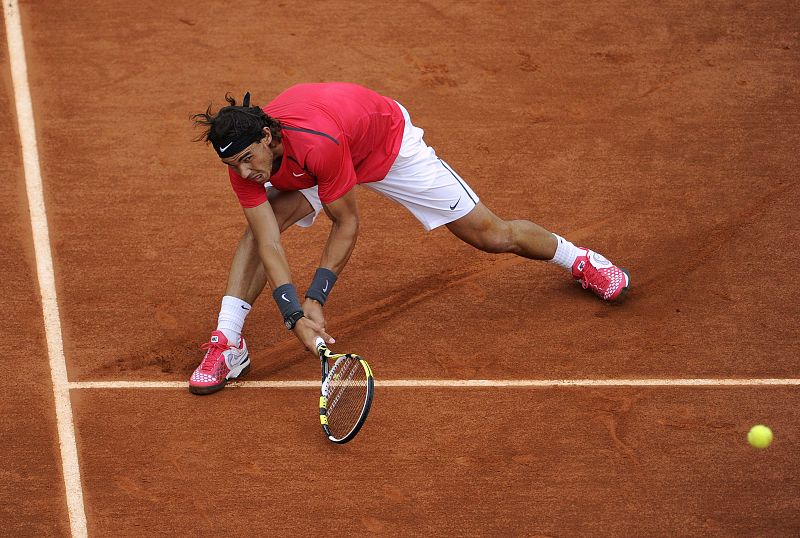 Rafa Nadal baja a la tierra para devolver la pelota.