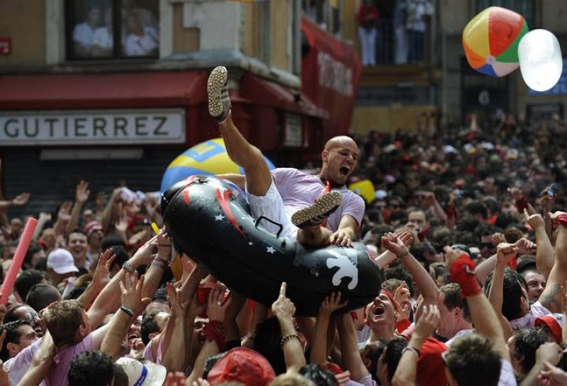 Un joven se divierte sobre una barca inflable en los Sanfermines