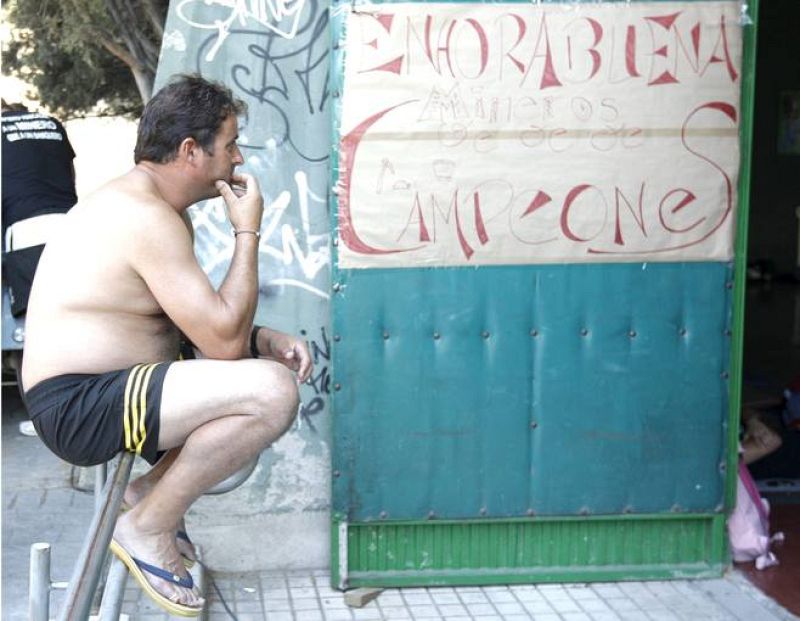 Un minero en la Ciudad Universitaria de Madrid junto a una pancarta de apoyo que dice enhorabuena campeones