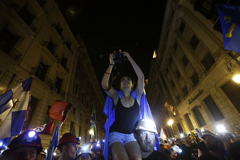 A coal miner carries a photographer on his shoulders as she takes pictures on the last day of the "Marcha Negra" in Madrid