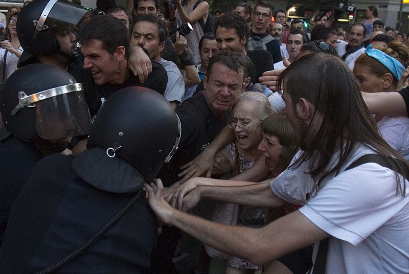 Riot police arrest a woman during a protest outside the Spanish socialist PSOE party headquarters in Madrid