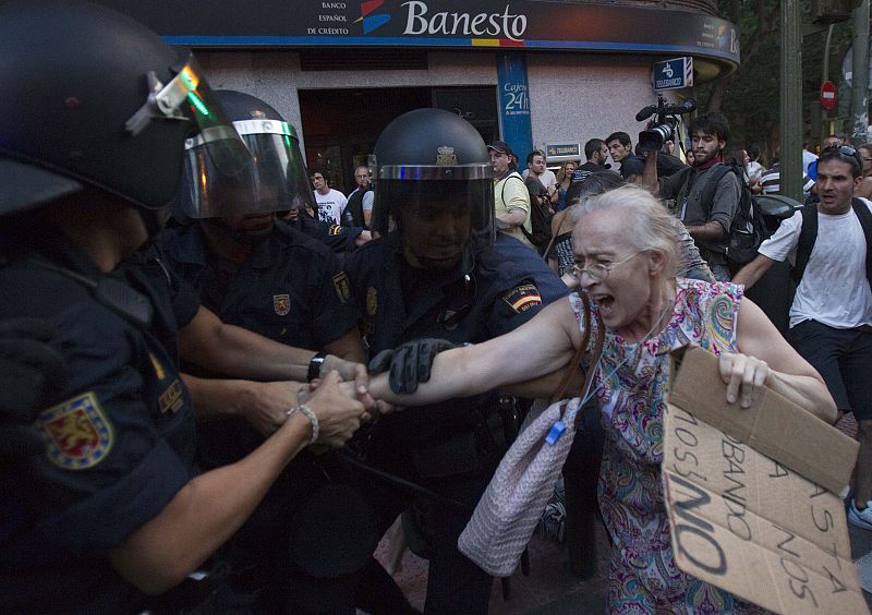 Riot police arrest a woman during a protest outside the Spanish socialist PSOE party headquarters in Madrid