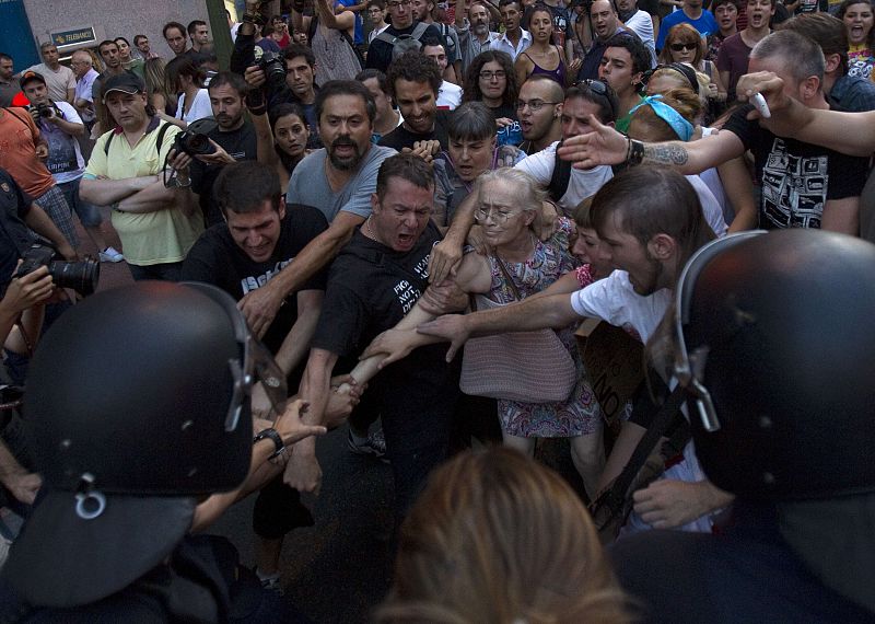 Riot police arrest a woman during a protest outside the Spanish socialist PSOE party headquarters in Madrid