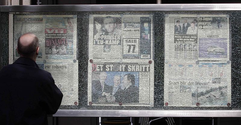 A man looks at a newspaper display, which shattered during the explosion on June 22, 2011 and is now a memorial, in Oslo