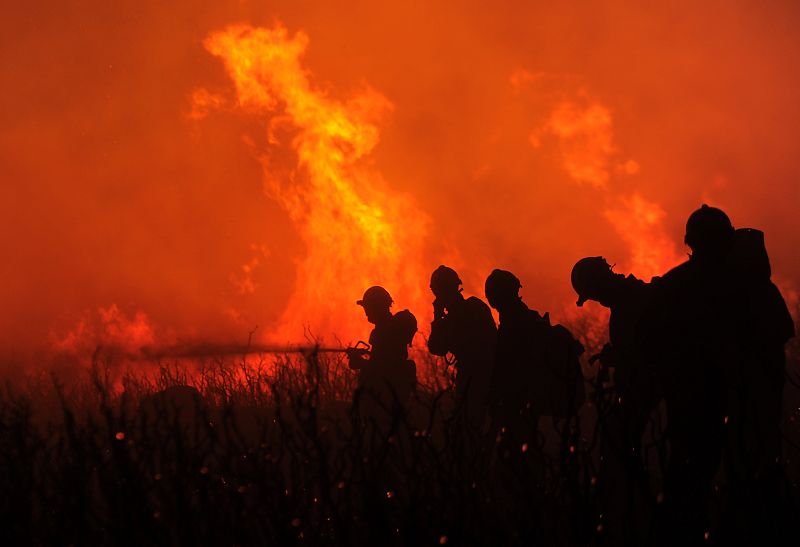Bomberos intentan extinguir el fuego en la frontera entre España y Francia donde se espera que se desplacen 400 efectivos de la Unidad Militar de Emergencias