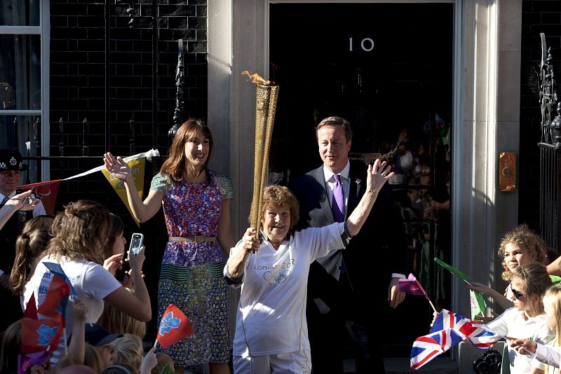 El primer ministro británico David Cameron y su esposa Samantha Cameron posan junto a Florence Rowe que porta la antorcha olímpica, frente al número 10 de Downing street en Londres.