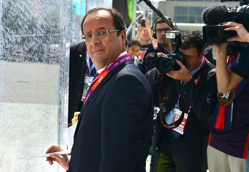 El presidente francés François Hollande firma durante su visita a la Villa Olímpica francesa en Londres.