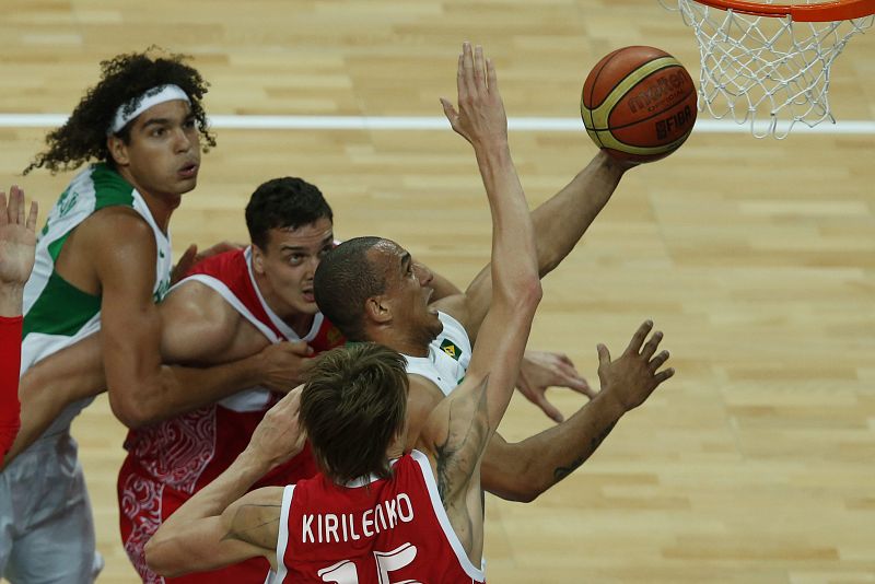 El escolta de Brasil Alex García (c) entra a canasta ante el alero de Rusia Andrei Kirilenko, durante su partido de la fase de grupos del torneo olímpico de baloncesto.