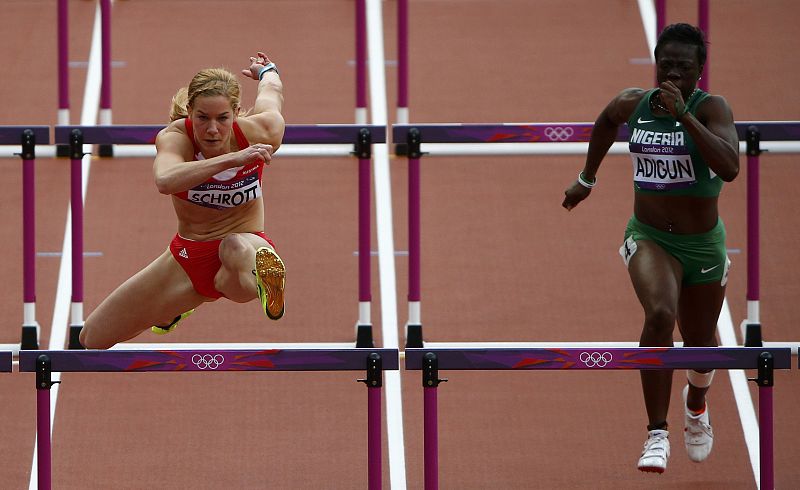 La austríaca Beate Schrott (L) compite con la nigeriana Seun Adigun en la primera ronda femenina de100 metros con vallas durante los Juegos.