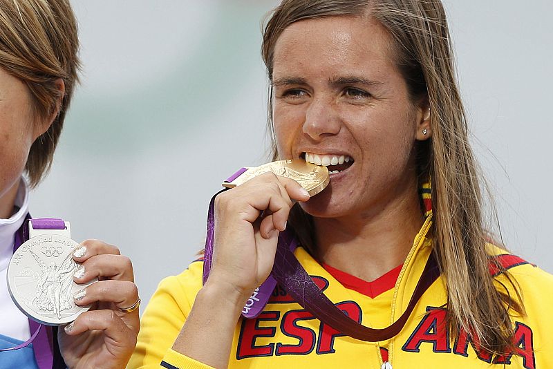 La española Marina Alabau, muerde la medalla de oro ante la finlandesa Tuuli Petaja, plata.