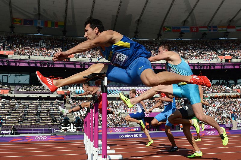 Oleksiy Kasyanov de Ucrania (delante) compite en el decatlón 110m con vallas de la categoría masculina en la fase de calificación del evento de atletismo durante los Juegos.