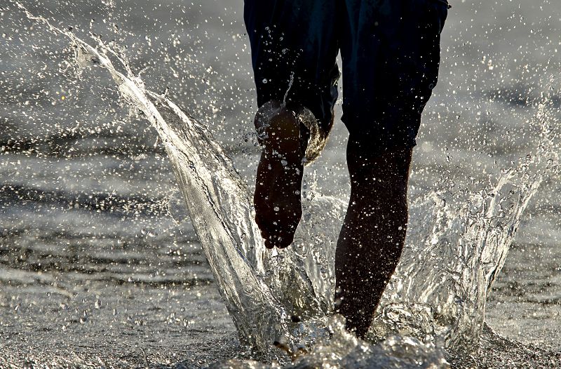 Un hombre corre por la orilla de la playa de la Zurriola de San Sebastián, en el Pais Vasco, donde se preve que las temperaturas alcancen los 39 grados