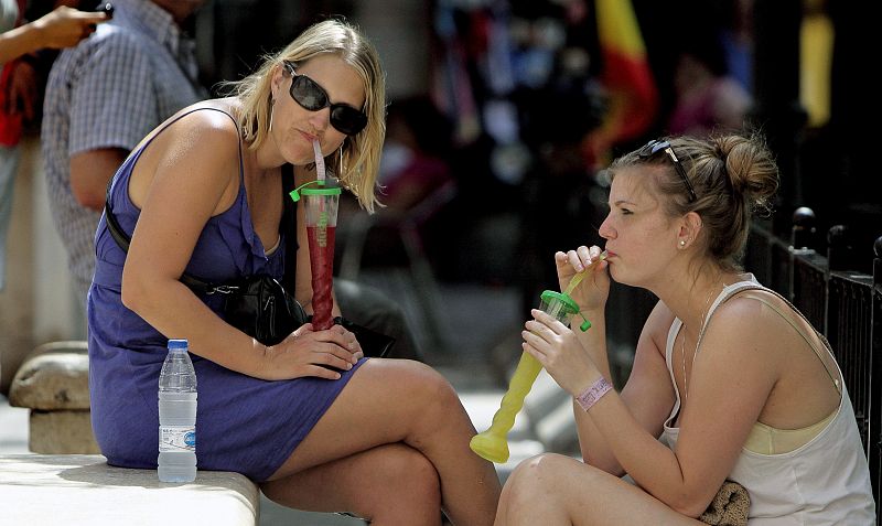 Dos turistas beben refrescos en la plaza de la Reina de Valencia para mitigar las altas temperaturas de la ola de calor