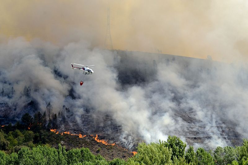 Un helicoptero sobrevuela una zona incendiada cercana al pueblo de A Veiga de Cascalla, desalojado a causa del indencio de O Barco de Valdeorras, en Ourense