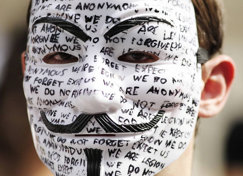 A protester wearing a mask waits for WikiLeaks founder Julian Assange to speak to the media outside the Ecuador embassy in west London