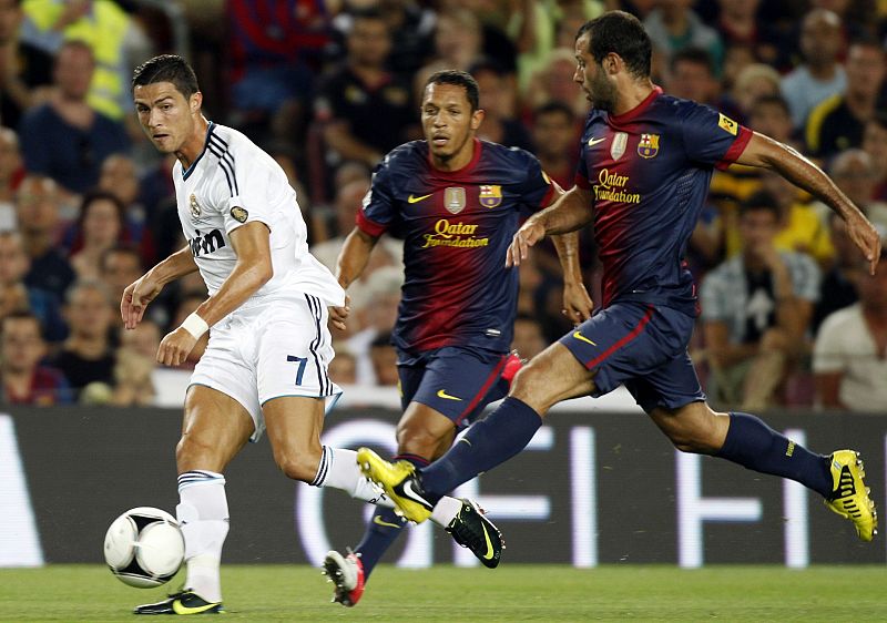 Cristiano Ronaldo intenta centrar ante los defensas del F.C. Barcelona Mascherano y Adriano.