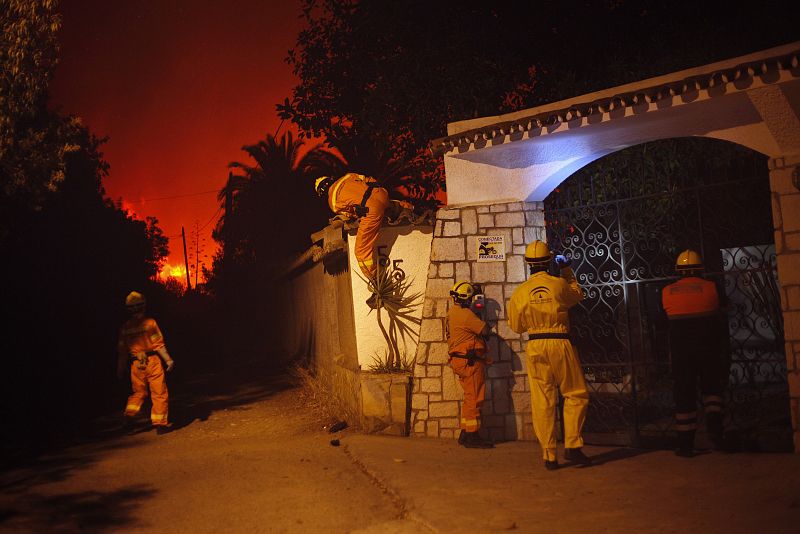 Miembros de Proteccion Civil buscan personas dentro de un chalet en Elviria, Malaga, durante la evacuacion general