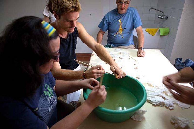 Varios voluntarios lavan las piezas recogidas en las excavaciones