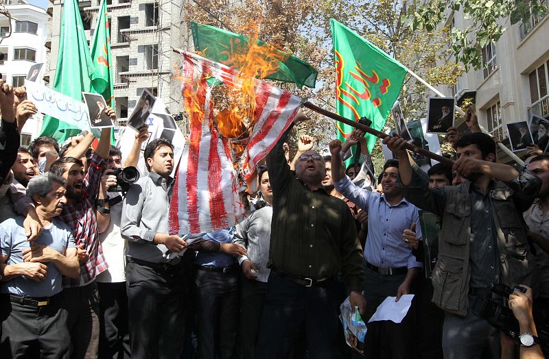 Manifestantes iraníes queman una bandera frente a la embajada de Suiza en Teherán. Suiza representa los intereses estadounidenses en Irán.