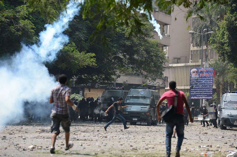 Un manifestante egipcio devuelve una granada de gas lacrimógeno a la policía en los enfrentamientos de este jueves