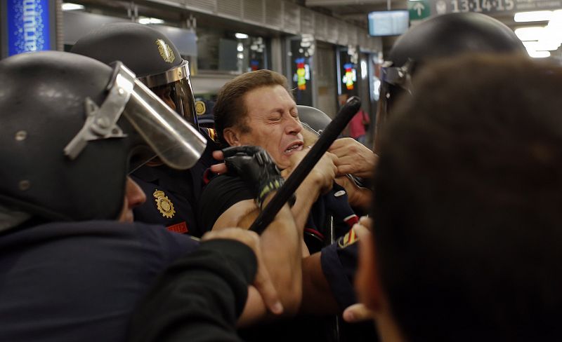 Un agente de policía detiene a uno de los miembros de los piquetes en Atocha