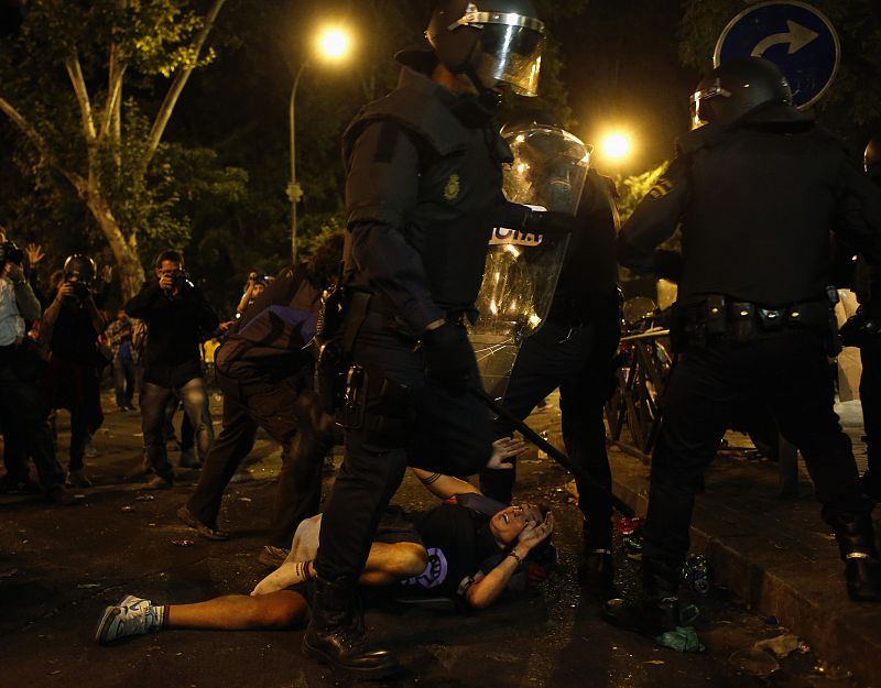 Protester reacts as riot police surround him outside Spanish parliament in Madrid