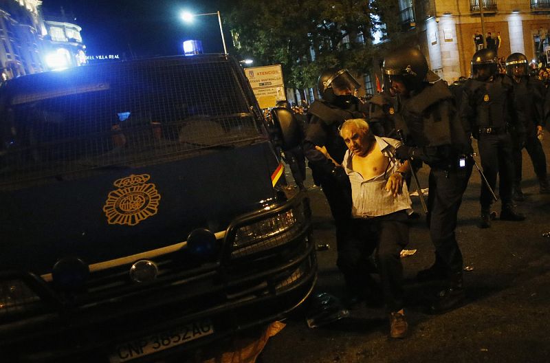 Riot police hold up demonstrator who was hit on head outside Spanish parliament in Madrid