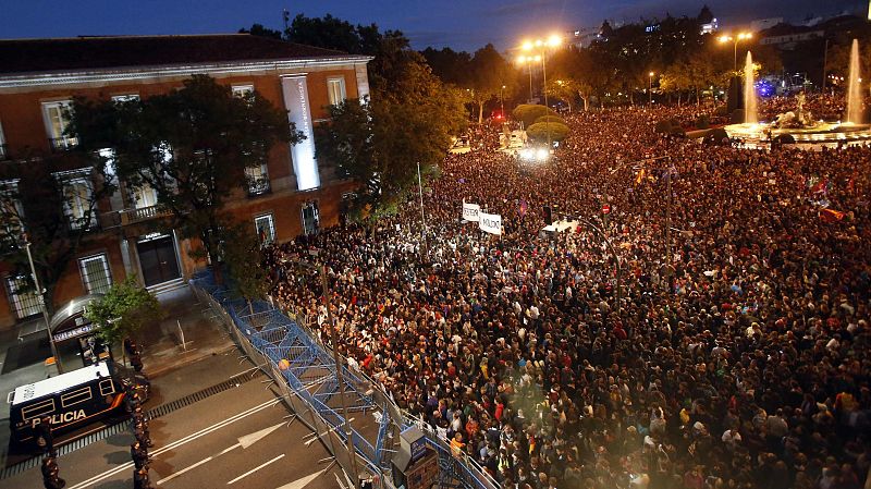 Protesters fill up Neptuno Square as National Police riot officers stand guard next to a barrier closing the street outside Spanish Parliament during a demonstration against government austerity measures in Madrid