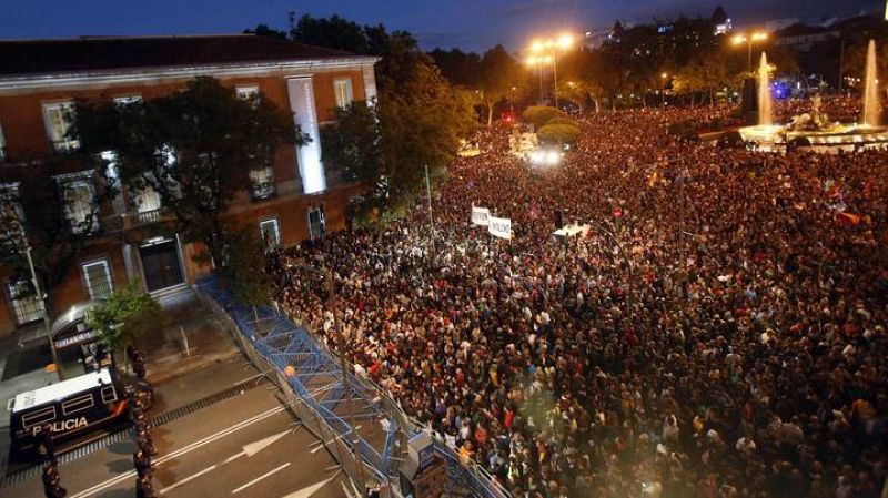 Protesters fill up Neptuno Square as National Police riot officers stand guard next to a barrier closing the street outside Spanish Parliament during a demonstration against government austerity measures in Madrid