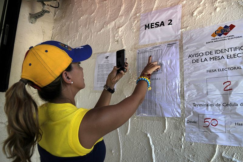 A Venezuelan voter searches for her vote number in a list during the presidential elections in front of the Venezuelan embassy in Santo Domingo