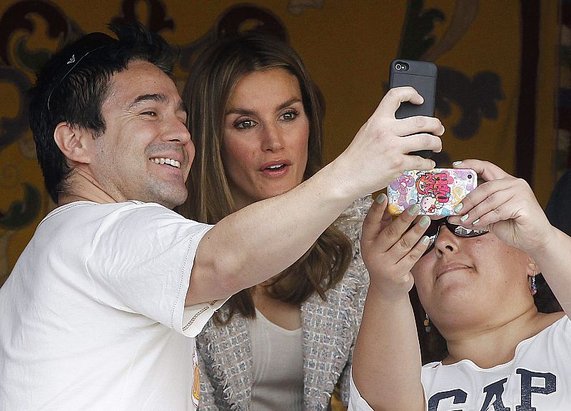 La princesa de Asturias se hace fotos con dos personas en la mesa de cuestación instalada en la Plaza de la Provincia, junto al Ministerio de Asuntos Exteriores.