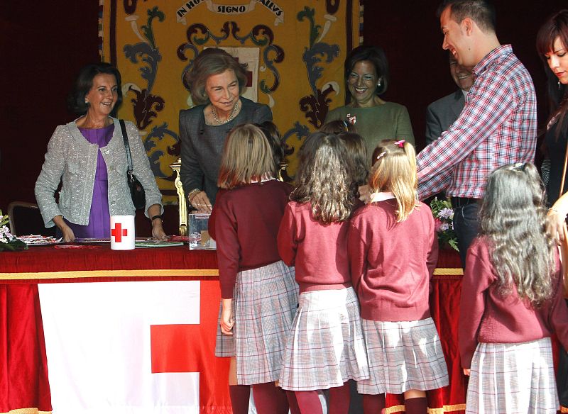 La reina con unas escolares en la mesa de cuestación instalada junto al Congreso de los Diputados, que ha presidido hoy en el "Día de la Banderita" de la Cruz Roja.