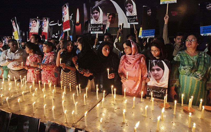 People hold candles and pictures of Malala Yousufzai at a school in Lahore