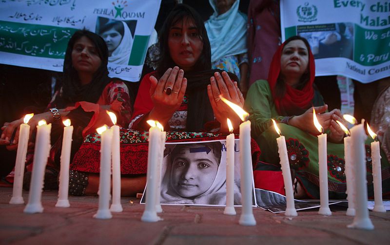 NCHD supporters pray next to pictures of schoolgirl Yousufzai, who was shot by the Taliban, during a candlelight vigil in Karachi